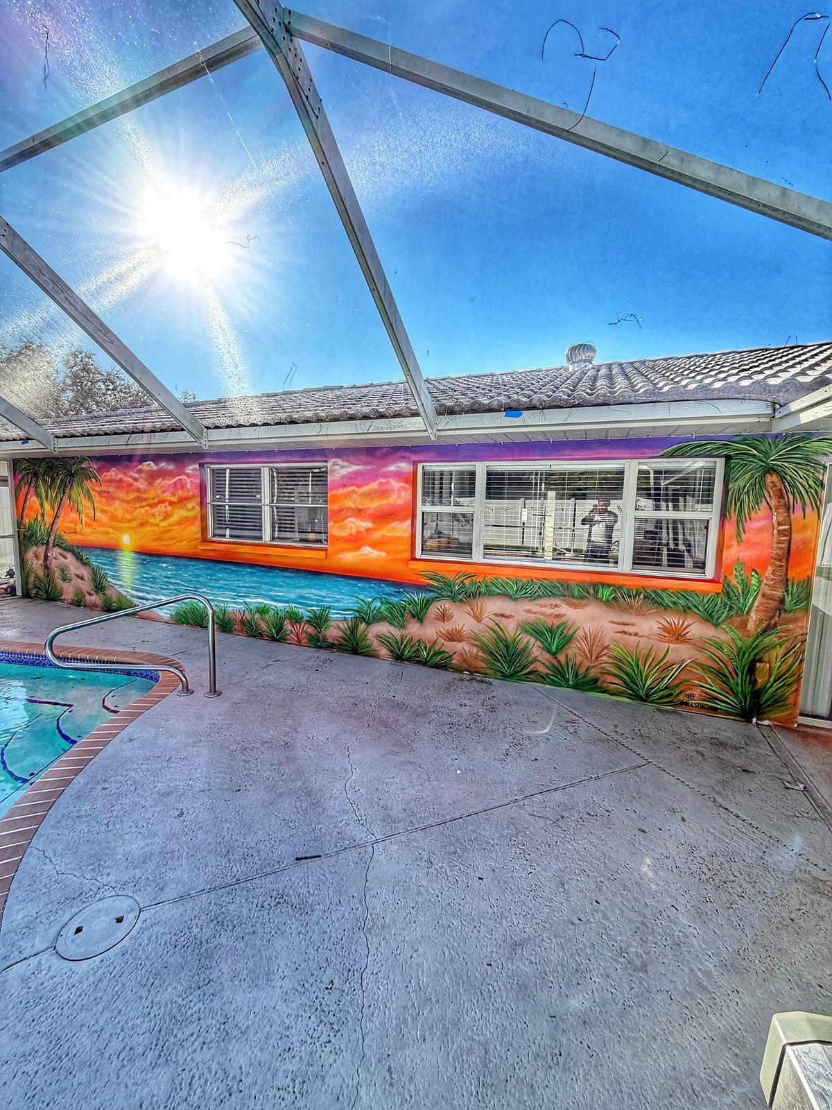 Sunset beach mural along a pool deck